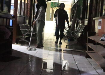 Mahasiswa sedang mengepel lantai yang digenangi air akibat kebocoran atap PKM, Sabtu (13/8/2022). (Genta Andalas/Geliz Luh Titisari)