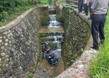 Warga mengevakuasi satu unit sepeda motor yang jatuh ke dalam parit saat kecelakaan, Jumat (16/09/2022). (Genta Andalas/M. Rivaldo)