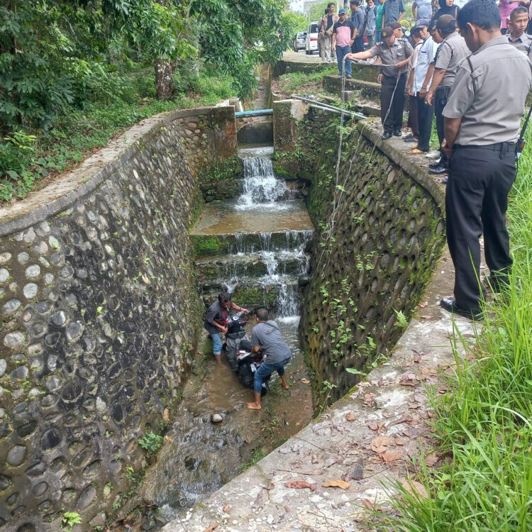 Warga mengevakuasi satu unit sepeda motor yang jatuh ke dalam parit saat kecelakaan, Jumat (16/09/2022). (Genta Andalas/M. Rivaldo)