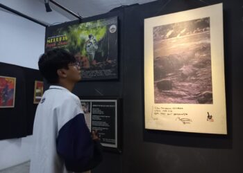 Salah seorang pengunjung sedang melihat jepretan foto yang dipamerkan pada pameran fotografi Tribute to 5AW, Sabtu (21/1/2023) (Genta Andalas/Bilqis Zehira Ramadhanti Ishak)