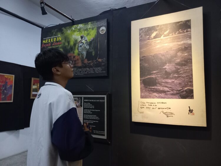 Salah seorang pengunjung sedang melihat jepretan foto yang dipamerkan pada pameran fotografi Tribute to 5AW, Sabtu (21/1/2023) (Genta Andalas/Bilqis Zehira Ramadhanti Ishak)
