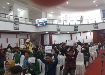 Sejumlah mahasiswa melakukan aksi angkat kertas sebagai sikap penolakan terhadap UU Cipta Kerja dalam Acara Workshop yang diadakan Satgas UU Cipta Kerja di Gedung Convention Hall UNAND pada Selasa ( 27/6/2023). ( Genta Andalas / Juniverman Yoga)