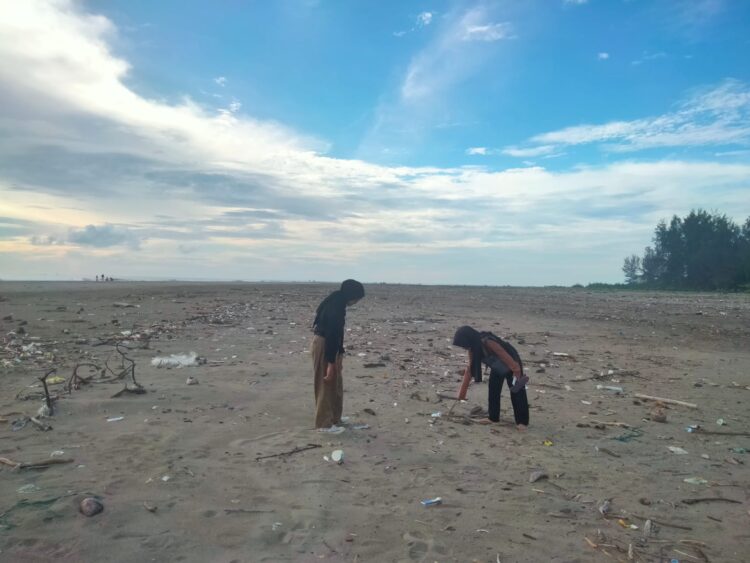 Pengunjung sedang memunguti sampah di Pantai Cinta, Pasir Jambak, Senin (22/1/2024) (Genta Andalas/Zulkifli Ramadhani)