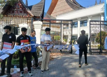 Koalisi Masyarakat Sipil membentangkan deretan kertas berisi catatan kasus kekerasan dan penyiksaan oleh aparat kepolisian Sumbar di depan Gedung DPRD, Kamis (26/06/25) (Genta Andalas/Alizah Fitri Sudira)