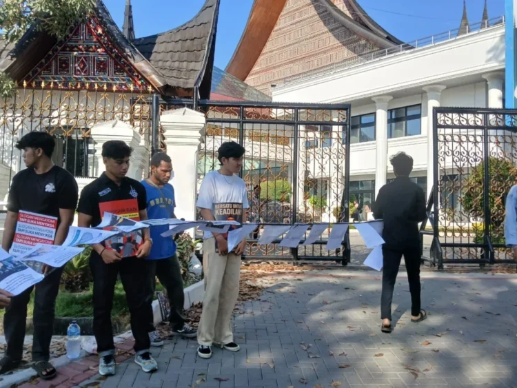 Koalisi Masyarakat Sipil membentangkan deretan kertas berisi catatan kasus kekerasan dan penyiksaan oleh aparat kepolisian Sumbar di depan Gedung DPRD, Kamis (26/06/25) (Genta Andalas/Alizah Fitri Sudira)