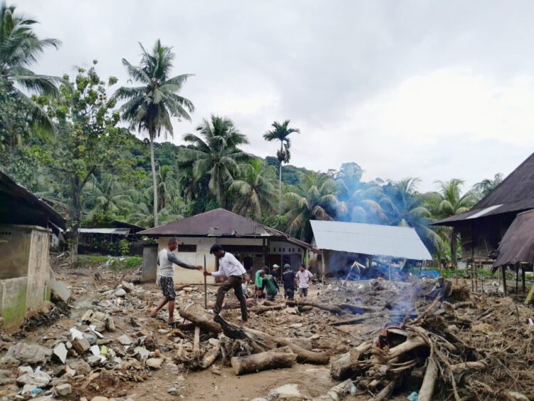 Warga membersihkan sisa material banjir di sekitar rumah mereka di kawasan Batu Busuk, Sabtu (28/12/2025). (Sabila Hayatul Dhi’fa/Genta Andalas)